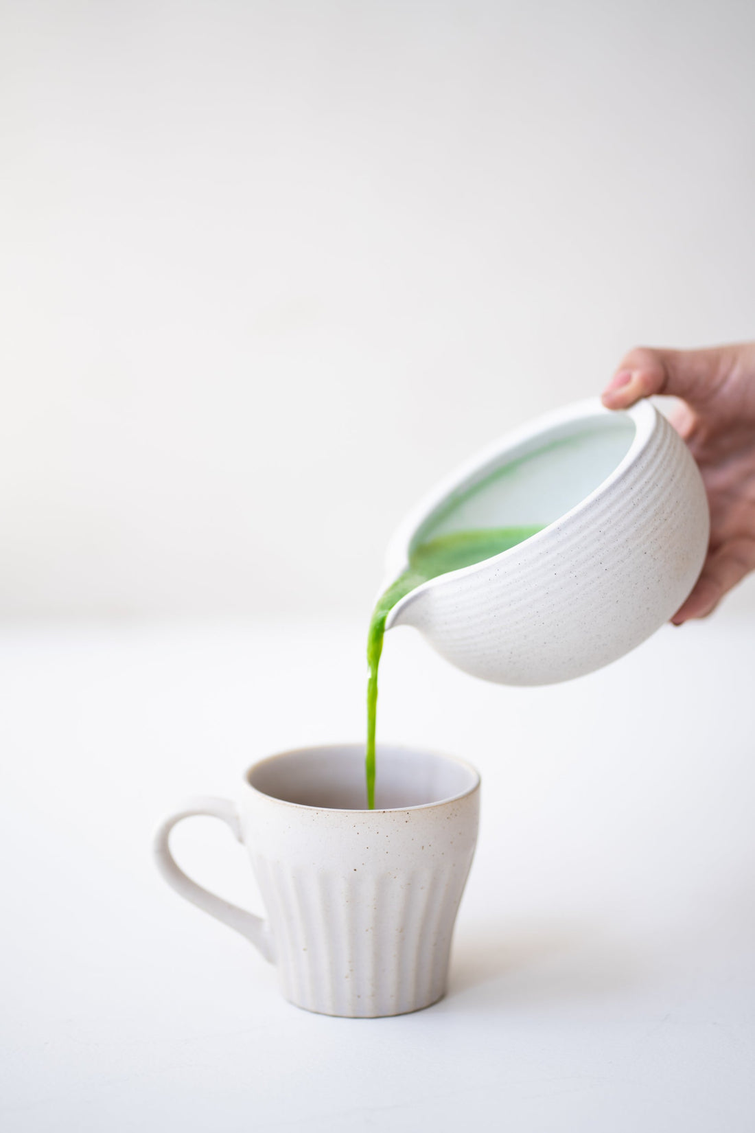 Matcha wird in eine weiße Tasse gegossen