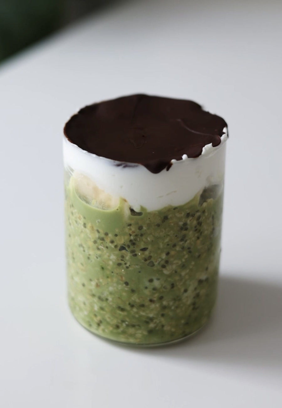Matcha Overnight Oats im Glas mit Chiasamen und Banane, bedeckt mit Joghurt und einer Schicht Schokolade